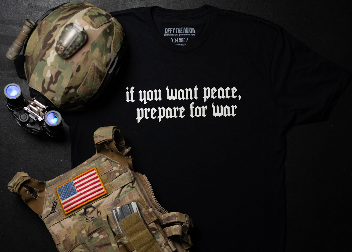 Black t-shirt with text, tactical vest, and helmet on a dark background
